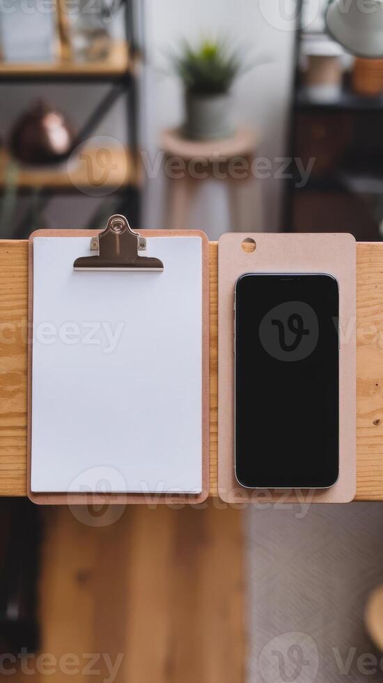 A smartphone and a clipboard on a wooden table photo
