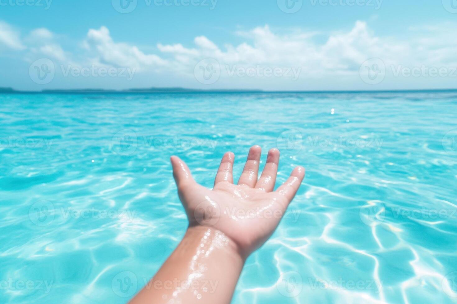 Hand reaching towards the sky in a clear blue ocean, sunlight shimmering on the turquoise water photo