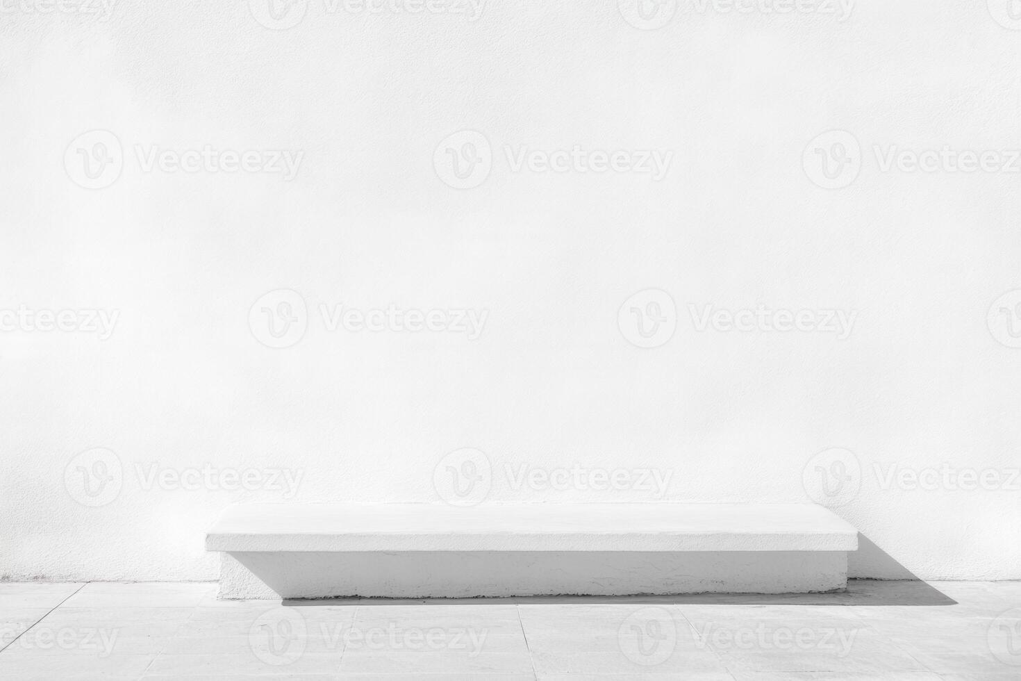 Minimalist white platform in front of textured white wall on a tiled floor, bathed in sunlight photo