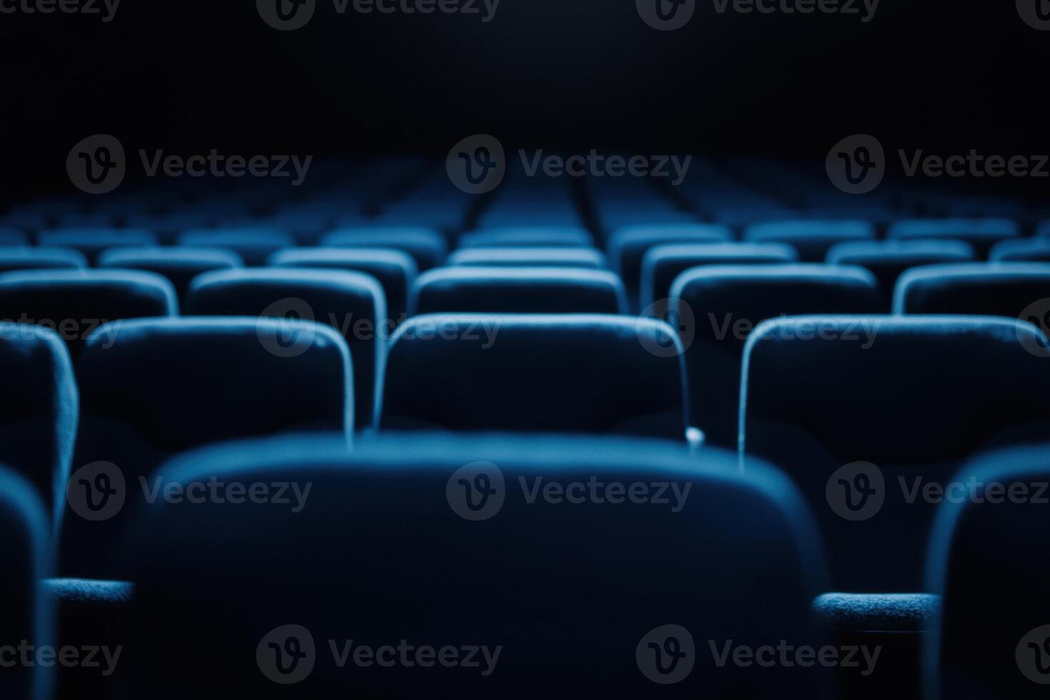 Rows of plush seating, bathed in a cool blue tone, await a captivated audience in the darkness photo