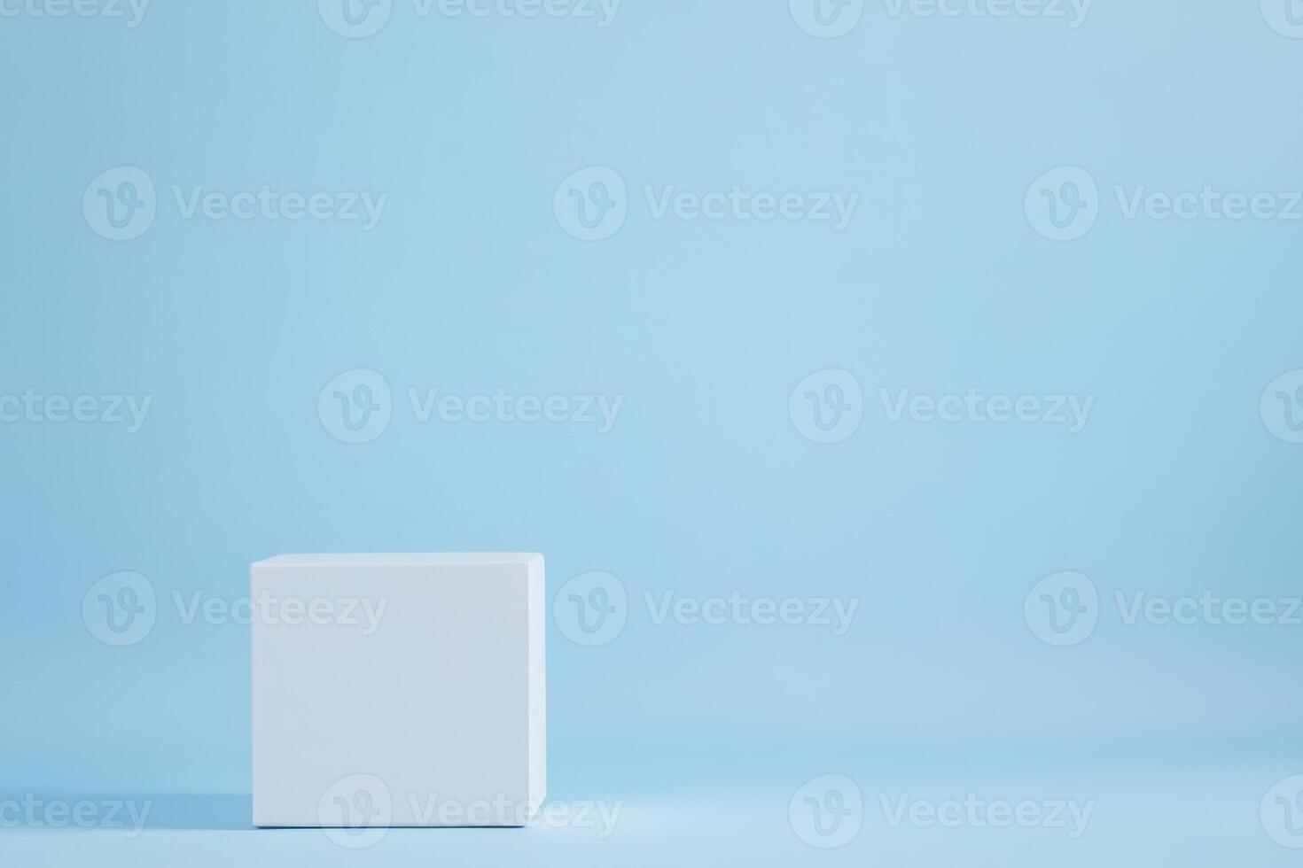 Minimalist cube display platform against a soft blue background. Clean geometric presentation photo