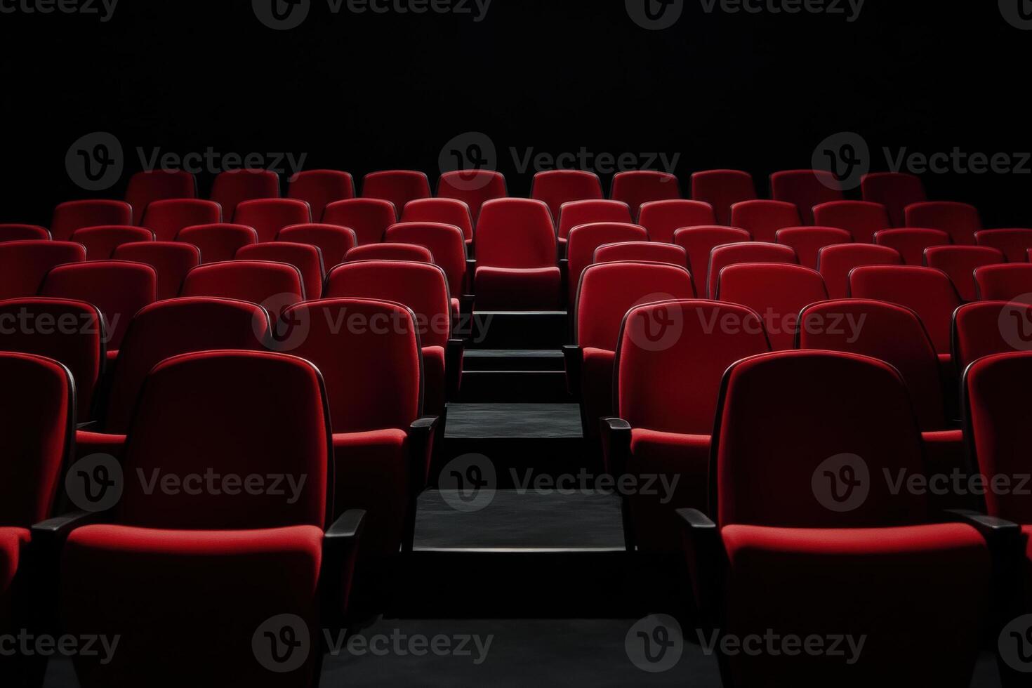 Rows of empty red seating in a dark movie theater or auditorium, awaiting an audience photo