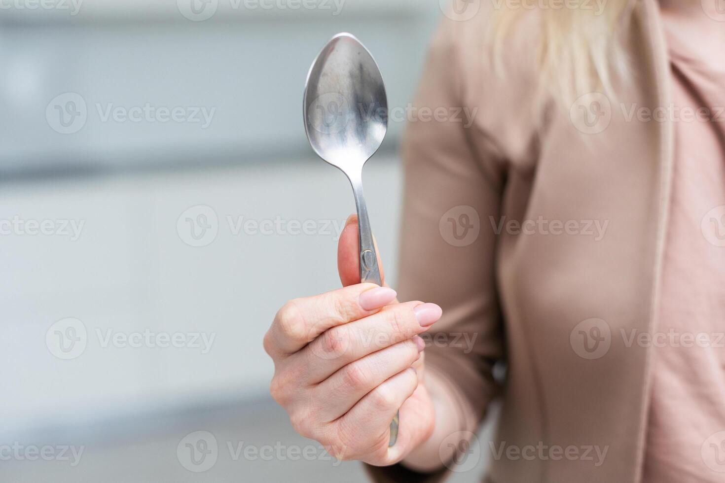 Metallic empty eating spoon in a human right hand with clipping path isolated on white photo