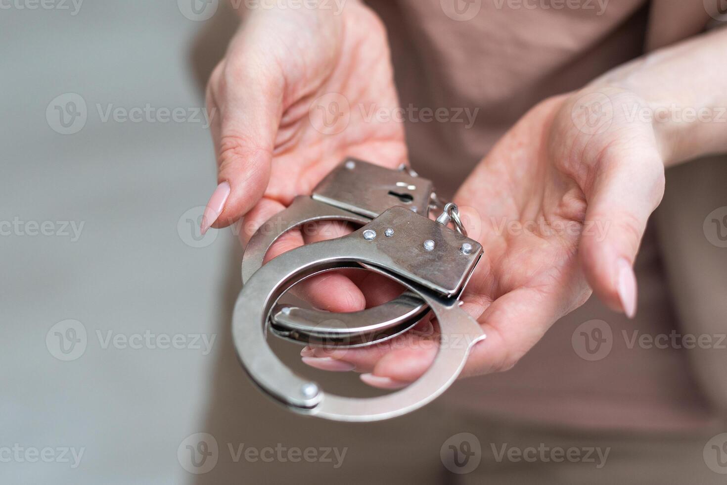 Metal handcuffs with a chain on a light background in a female hand photo