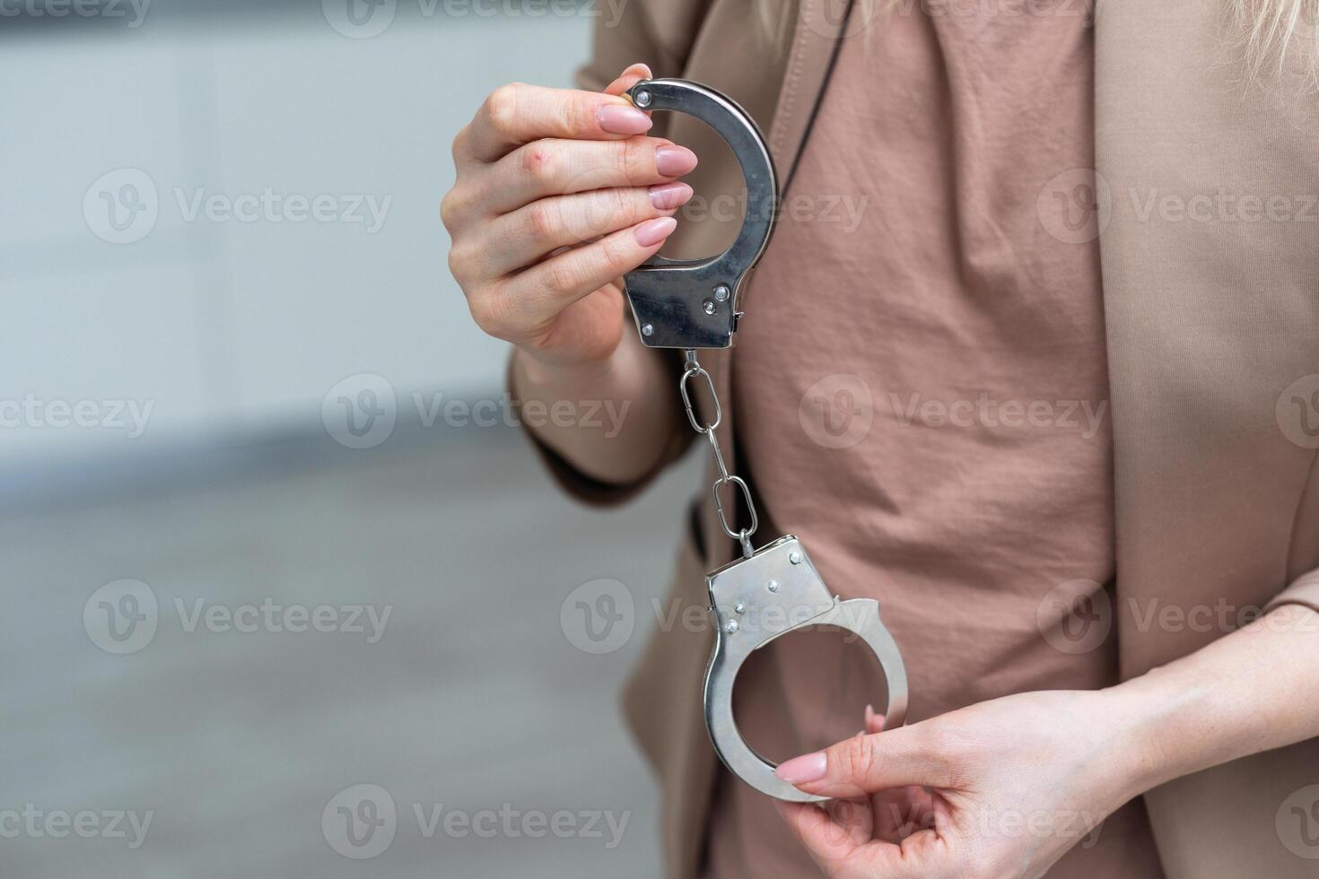 Metal handcuffs with a chain on a light background in a female hand photo