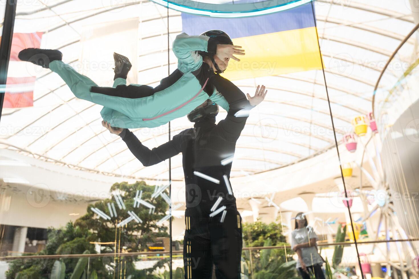 Excited teenage girl in helmet flying in aerodynamic tube wind tunnel. Skydiving training. photo