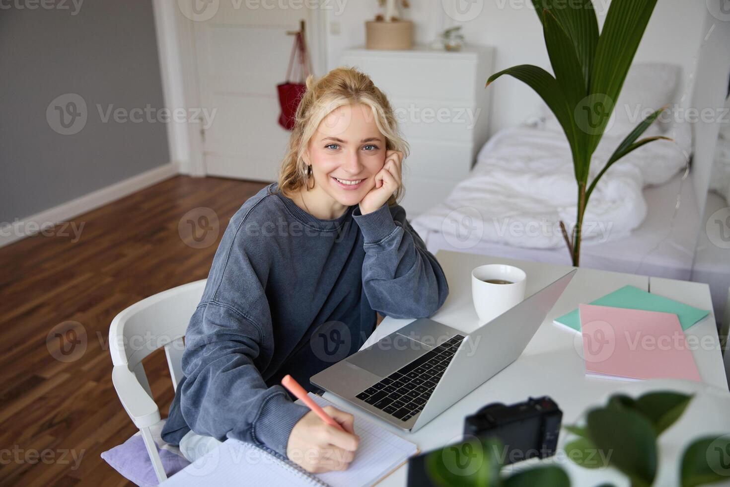 Portrait of young woman distance learning, working from home with laptop, making notes, student studying on remote, doing online course photo