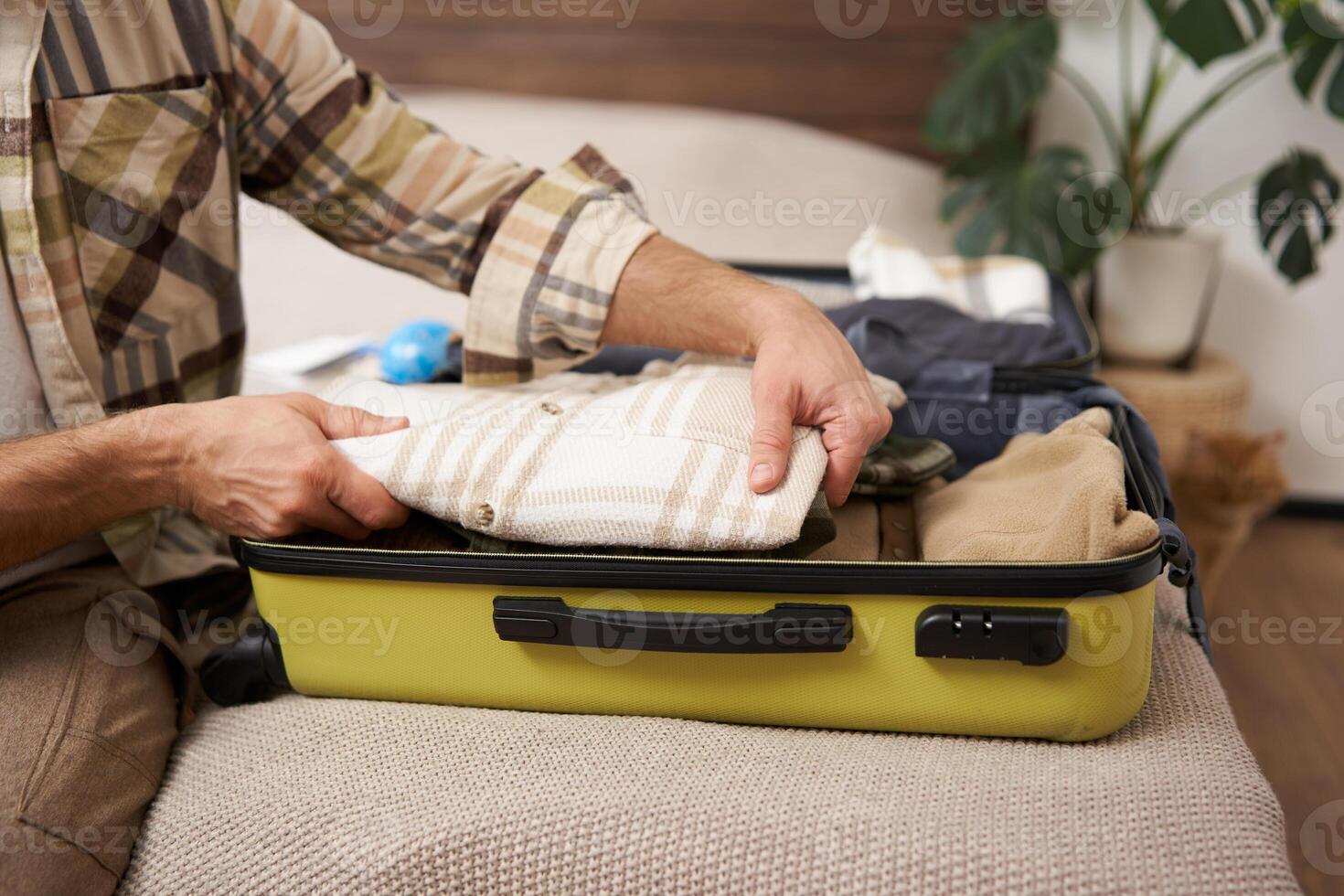 Cropped shot of hands packing clothes in luggage, going on vacation and prepared his suitcase, organises his items inside bag, packs for holiday photo