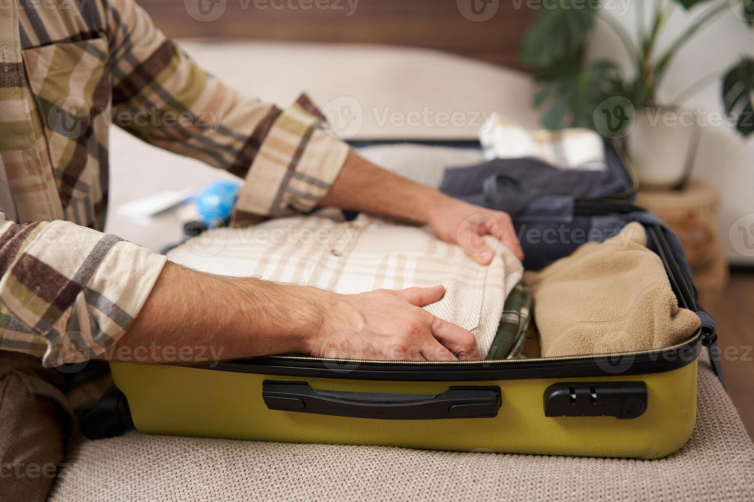 Male hands, tourist packing his clothes in luggage, putting items inside suitcase, getting ready for a vacation, going on holiday or business trip photo
