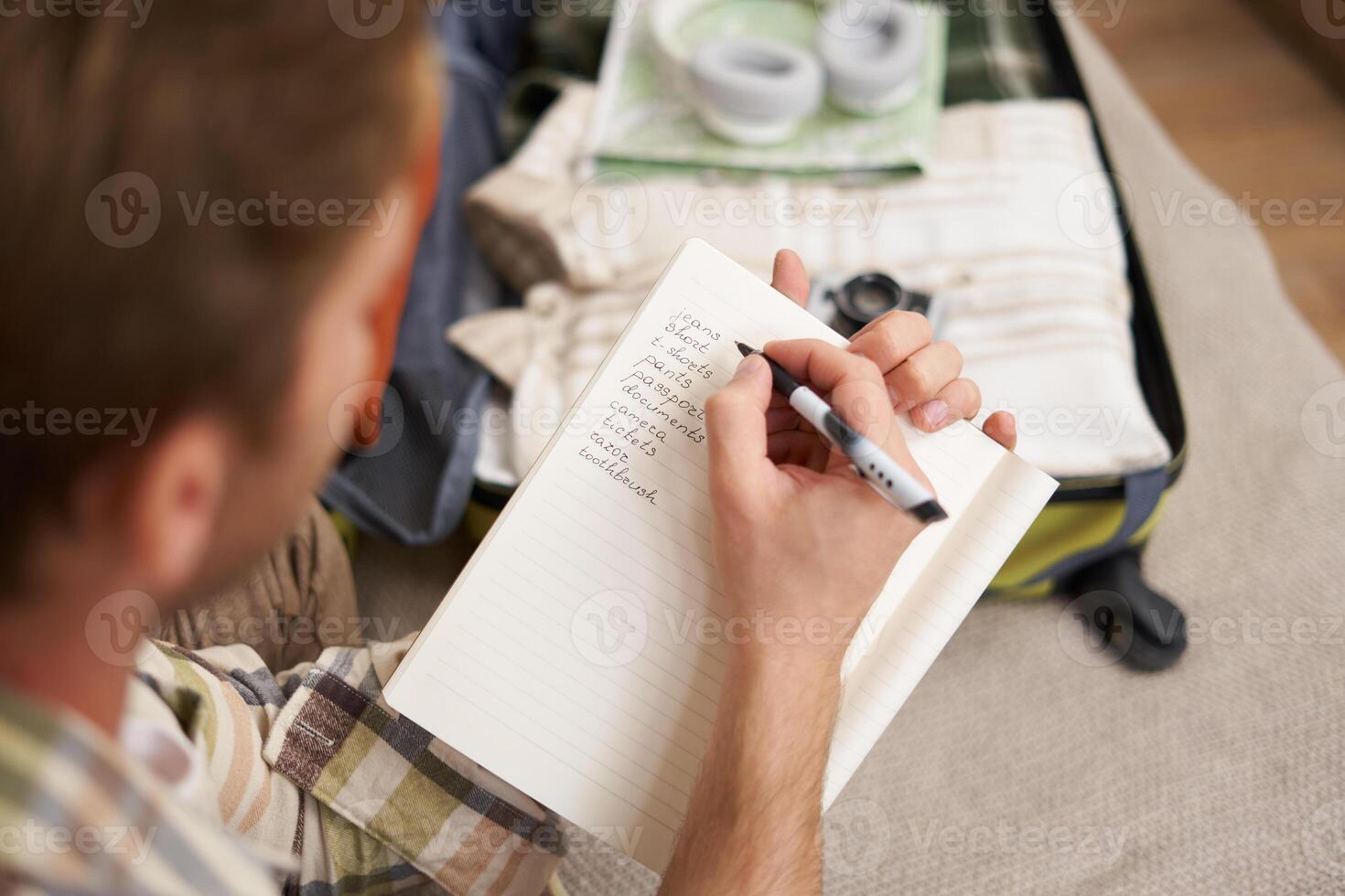 Close up portrait of man going through check-list, packing for holiday, looking at items he wants to bring on vacation photo