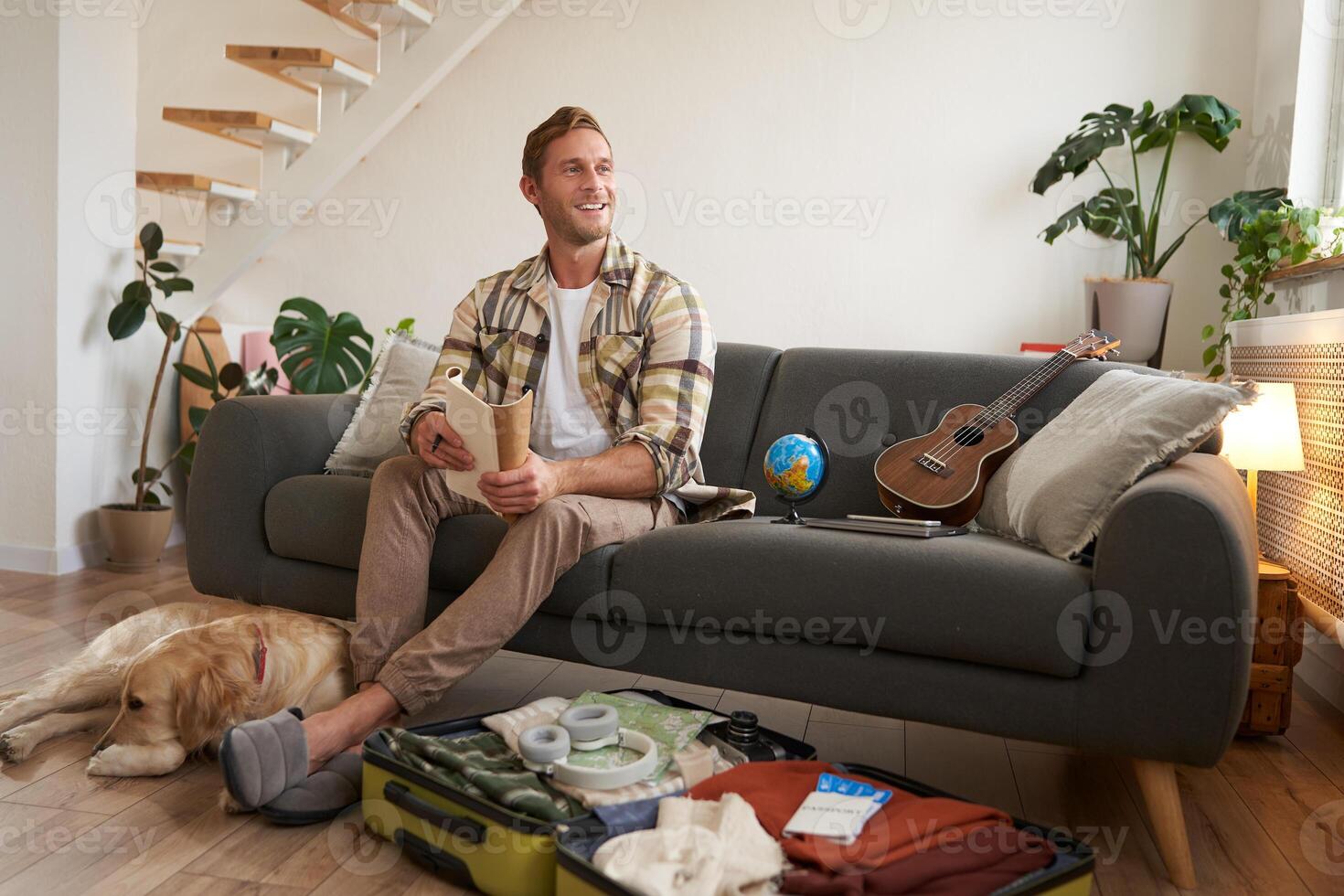 Portrait of man sitting with his dog, packing suitcase for a holiday, going on trip with a pet photo