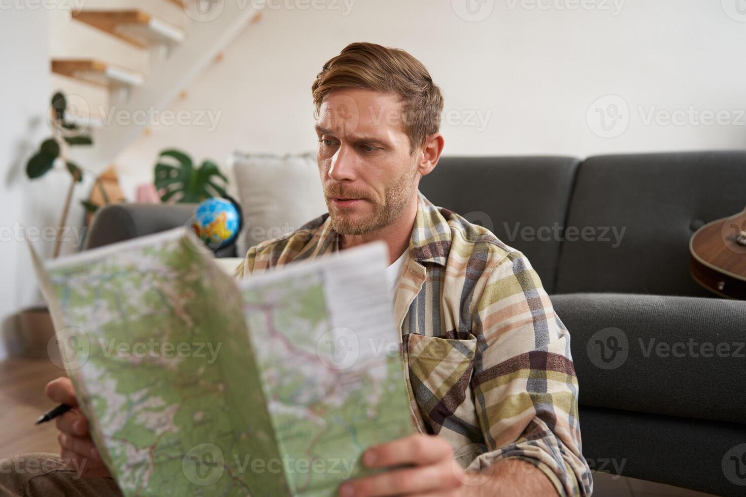 Portrait of man, traveller looks confused at map, studying the route to go on vacation or business trip photo