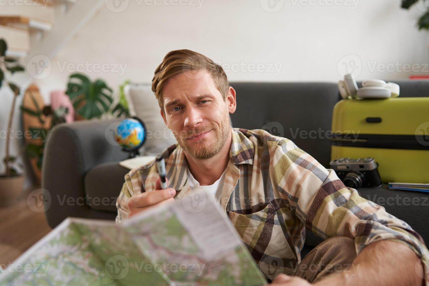 Smiling handsome man, traveller going on holiday, holding road map, planning his holiday, choosing the route photo