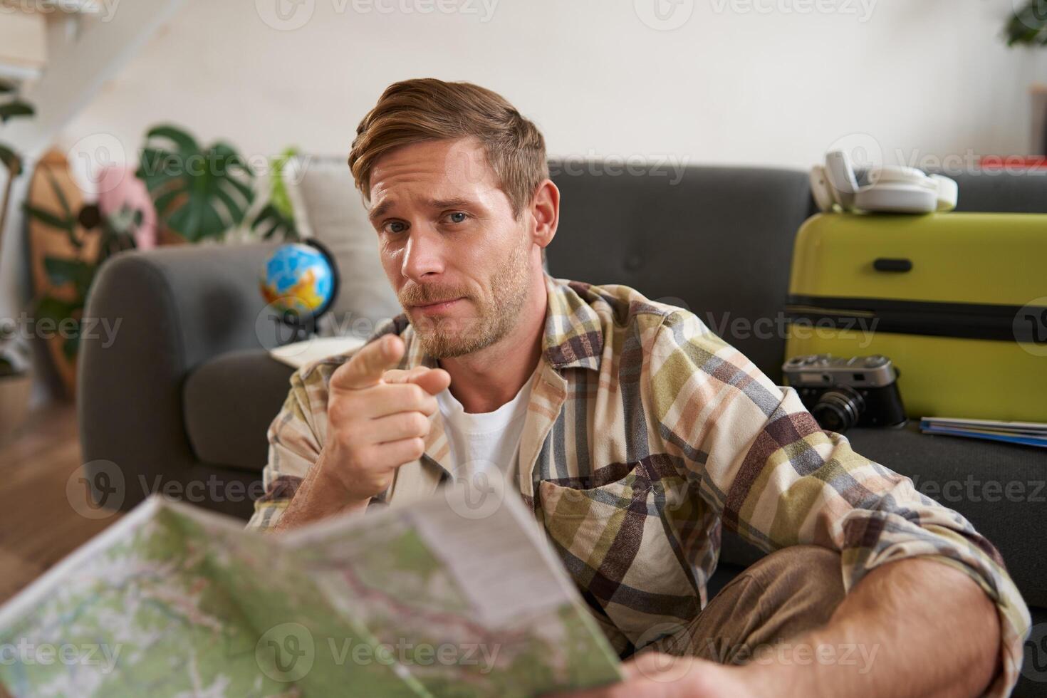 Portrait of handsome man, tourist, pointing finger at you, holding road map, going on holiday photo