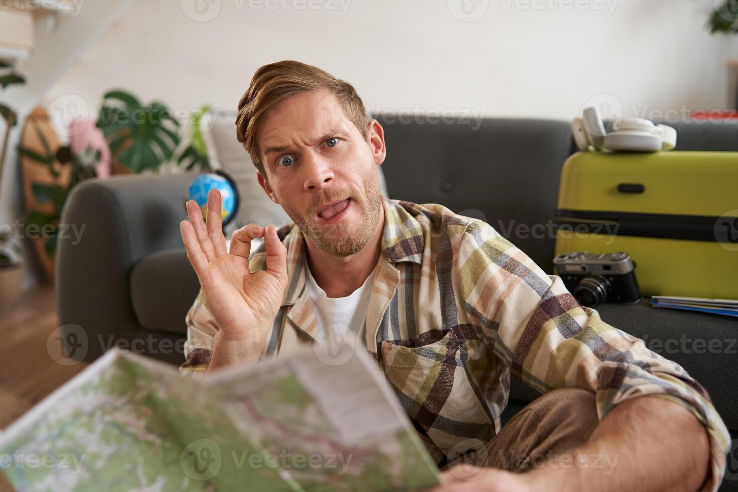 Good-looking guy, tourist with travel map, shows okay, ok sign, approve route or holiday destination photo