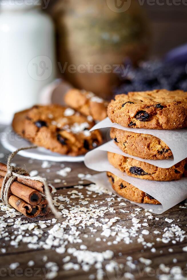 Homemade oatmeal cookies with nuts and raisins and glass of milk on dark wooden background, closeup, selective focus photo