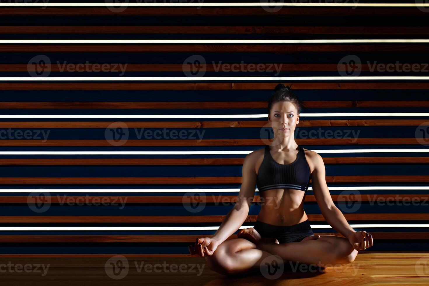 Young woman doing yoga exercises in dark studio. Health lifestyle concept. photo