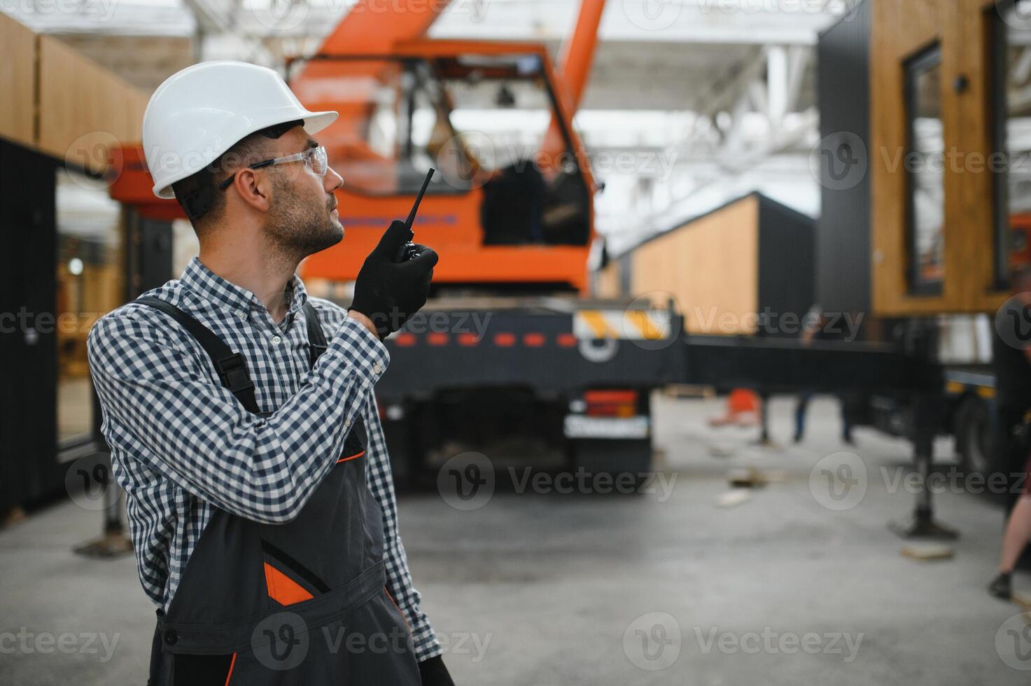 Foreman manages the loading of a prefabricated modular house to truck using walkie talkie photo