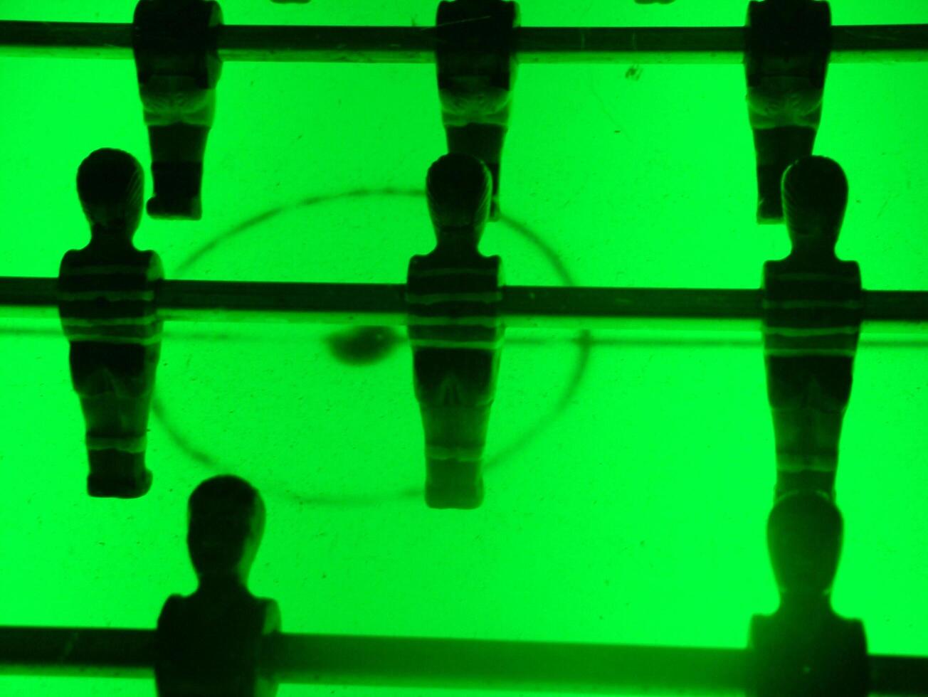 A retro-illuminated foosball table with a vibrant green glow creates an energetic and nostalgic atmosphere, perfect for adding a playful touch to any setting. photo
