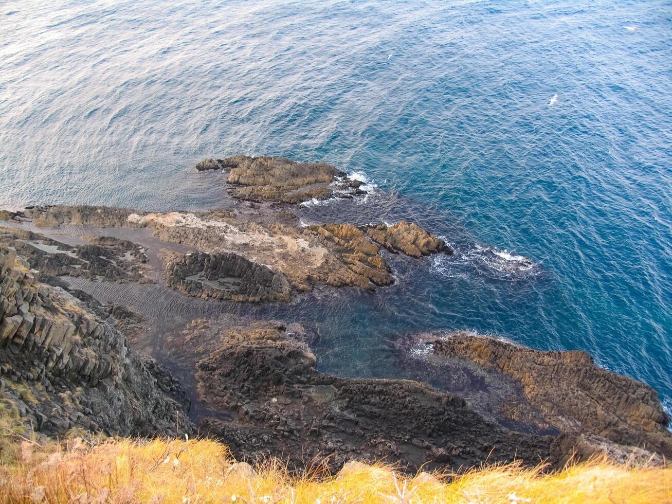 Rocky shore off coast of Japan. Frozen lava flows in the form of hexagonal. photo