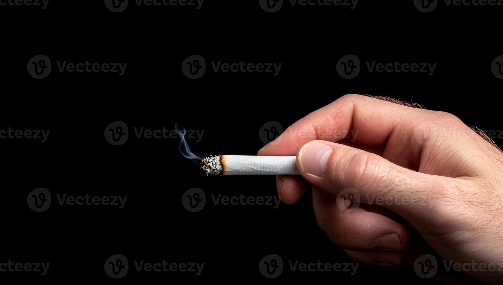 A hand holding a cigarette on a black background photo