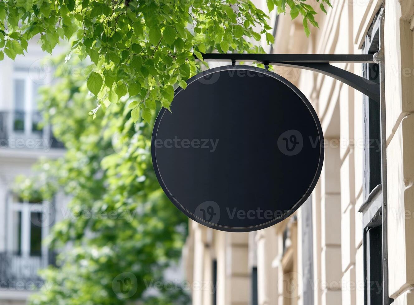 A blank sign hangs from a building, surrounded by green leaves. photo