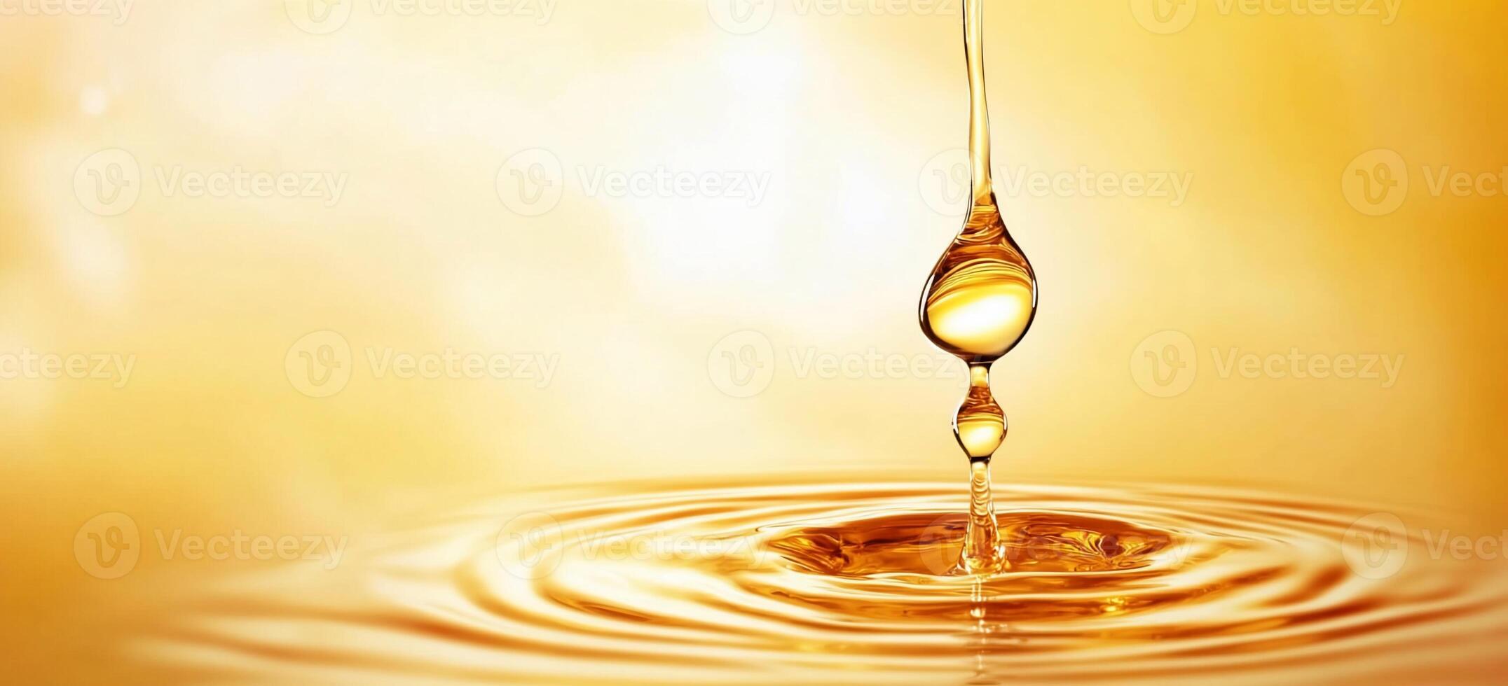 A droplet of golden liquid falling into a rippling surface. photo