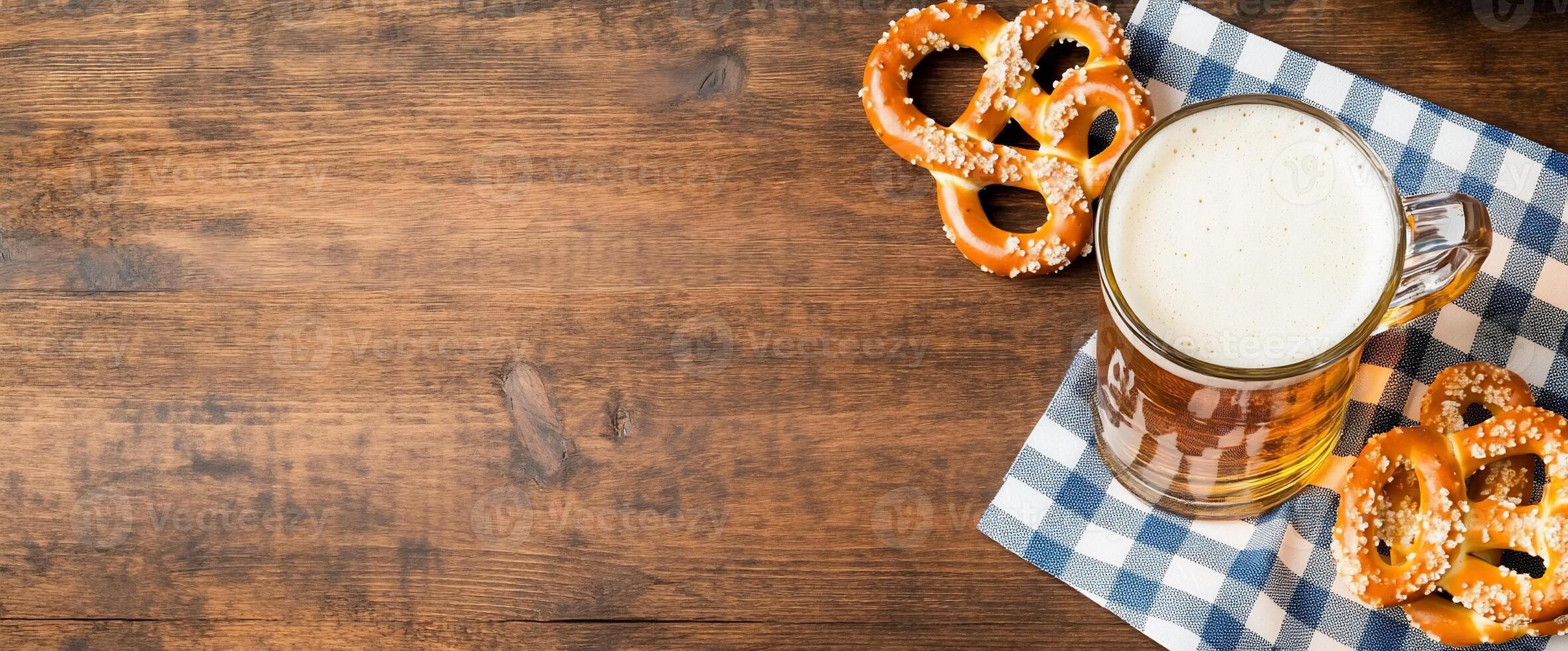 A frothy beer mug beside pretzels on a checkered cloth. photo