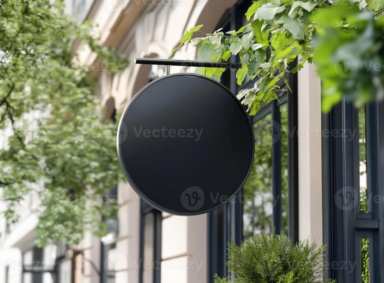 A round black sign hanging outside a building, surrounded by greenery. photo