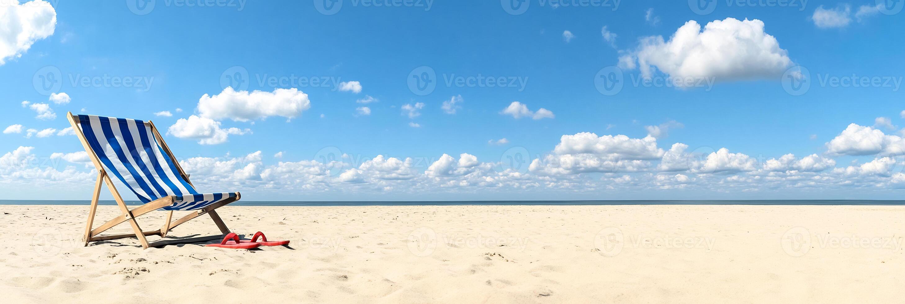 A serene beach scene with a striped deck chair under a blue sky. photo