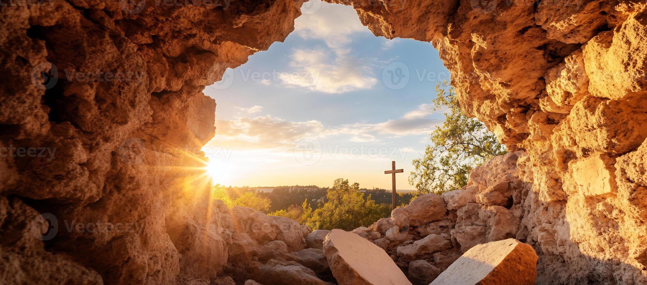 A serene view from a cave with a cross and sunset in the background. photo