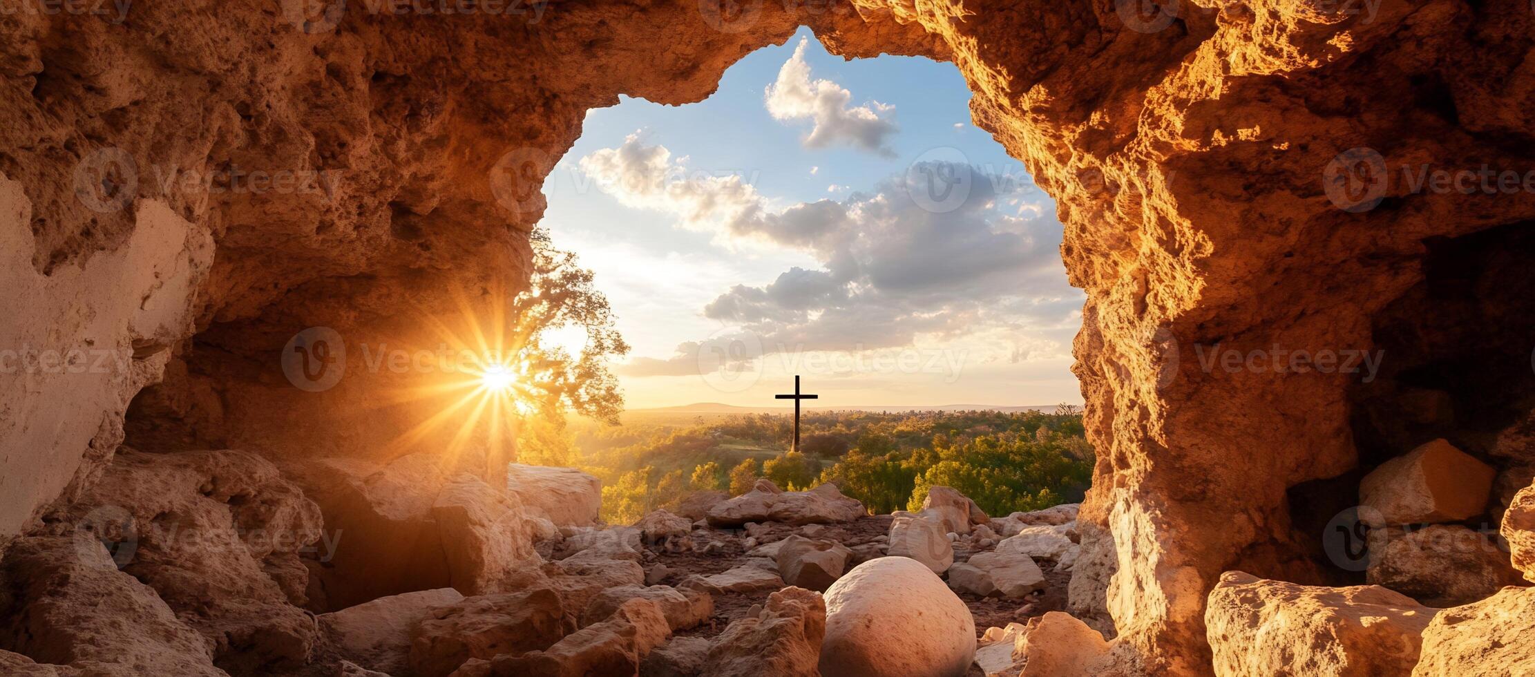 A serene view from a rocky cave with a cross at sunset. photo