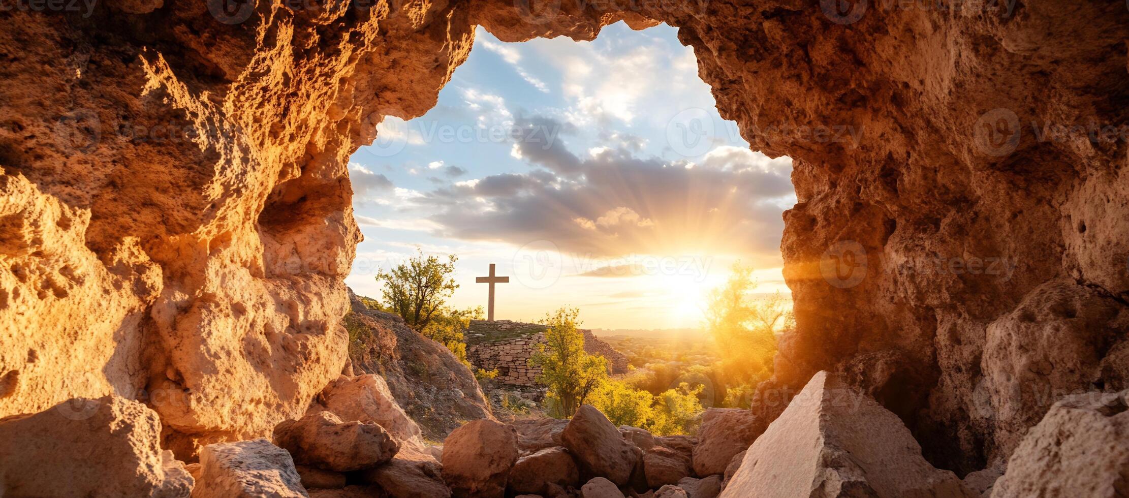 A serene view from a rocky opening, featuring a cross at sunset. photo