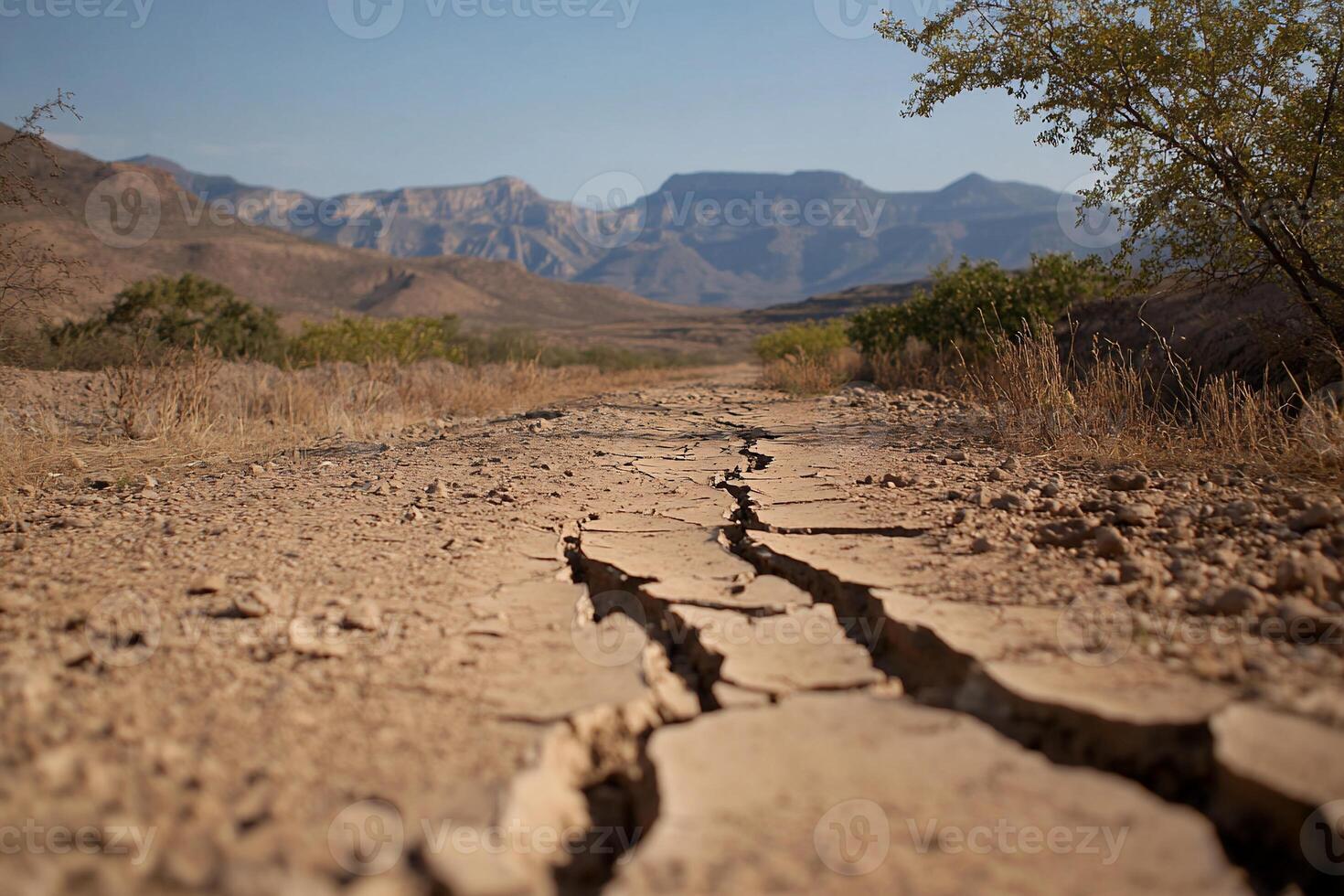 Cracked dry earth in a mountainous landscape under a clear sky. photo