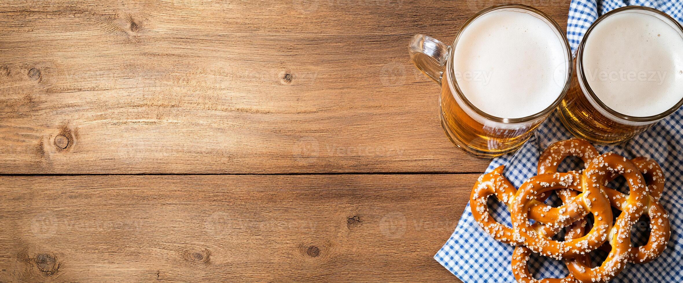 Two mugs of beer with pretzels on a wooden table setting. photo