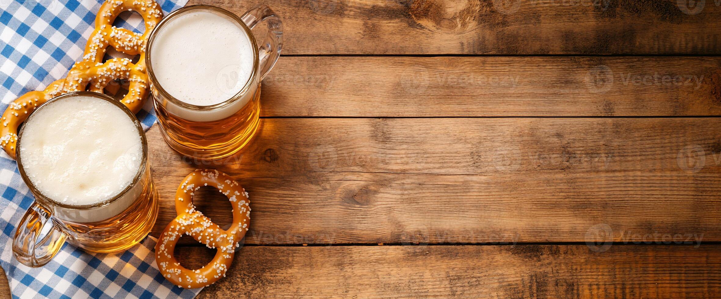Two mugs of beer with pretzels on a checkered cloth over wooden table. photo