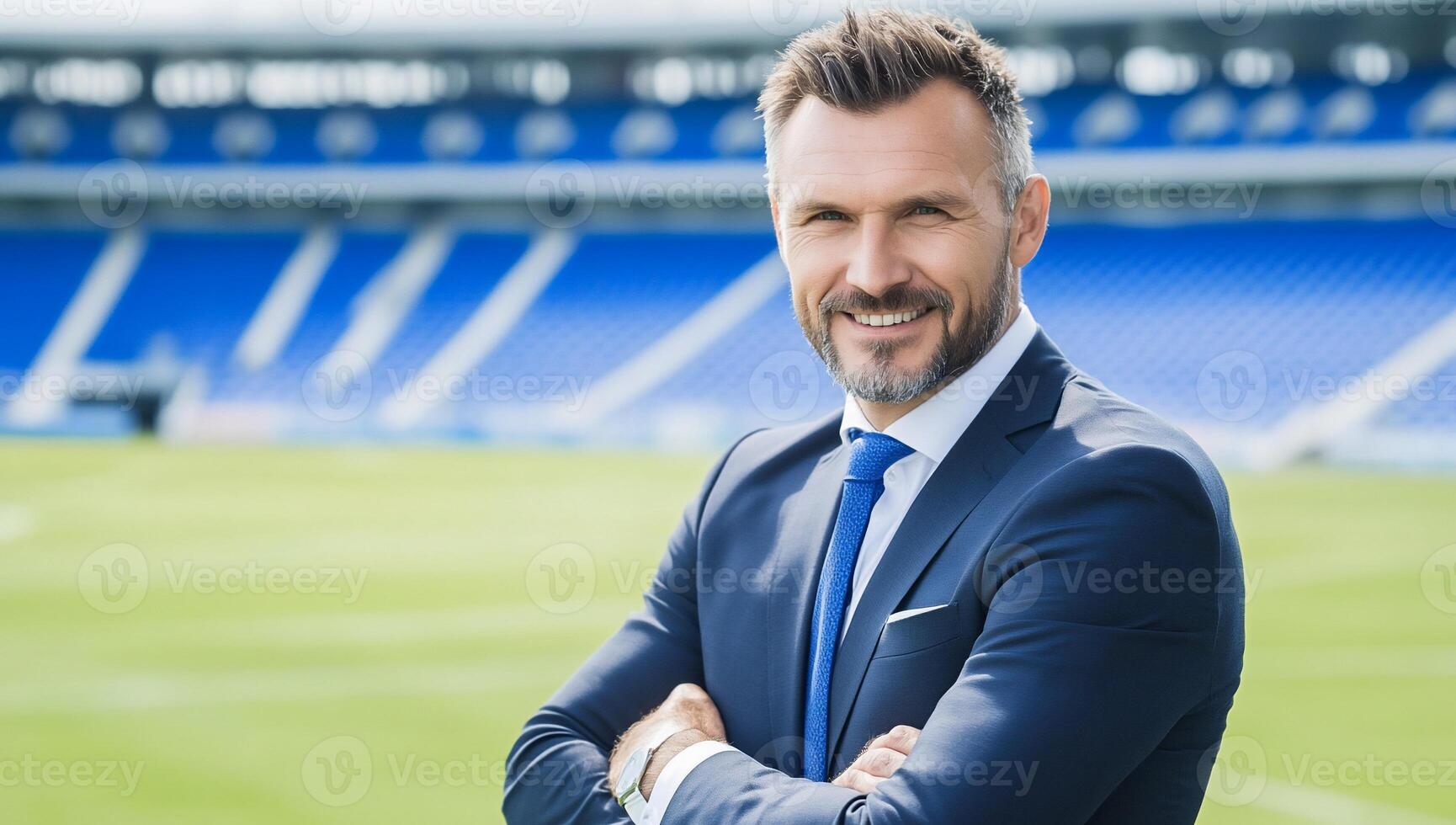 A confident man in a suit stands in a sports stadium. photo