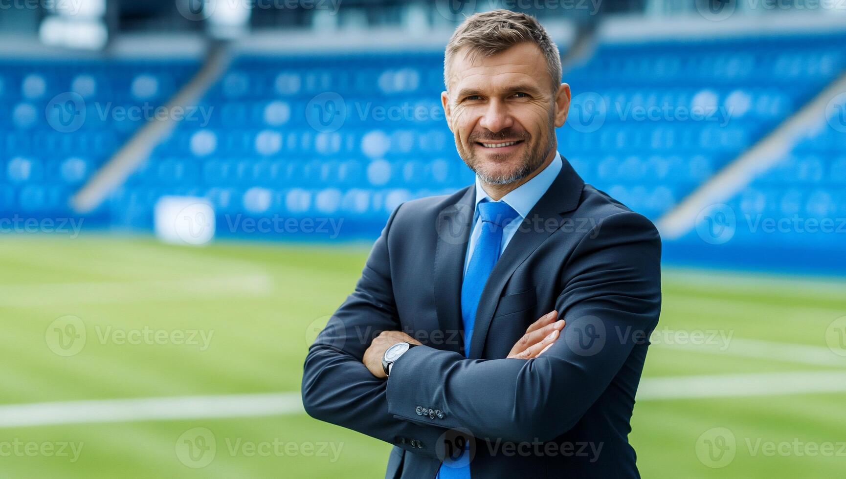A man in a suit and tie standing in front of a soccer field photo