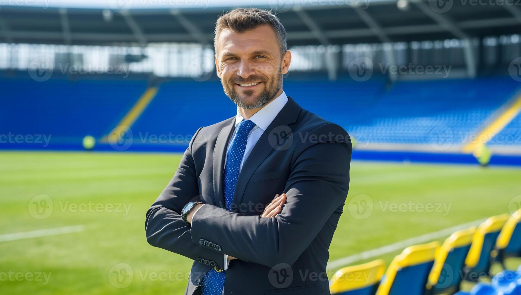 A man in a suit standing in front of a stadium photo