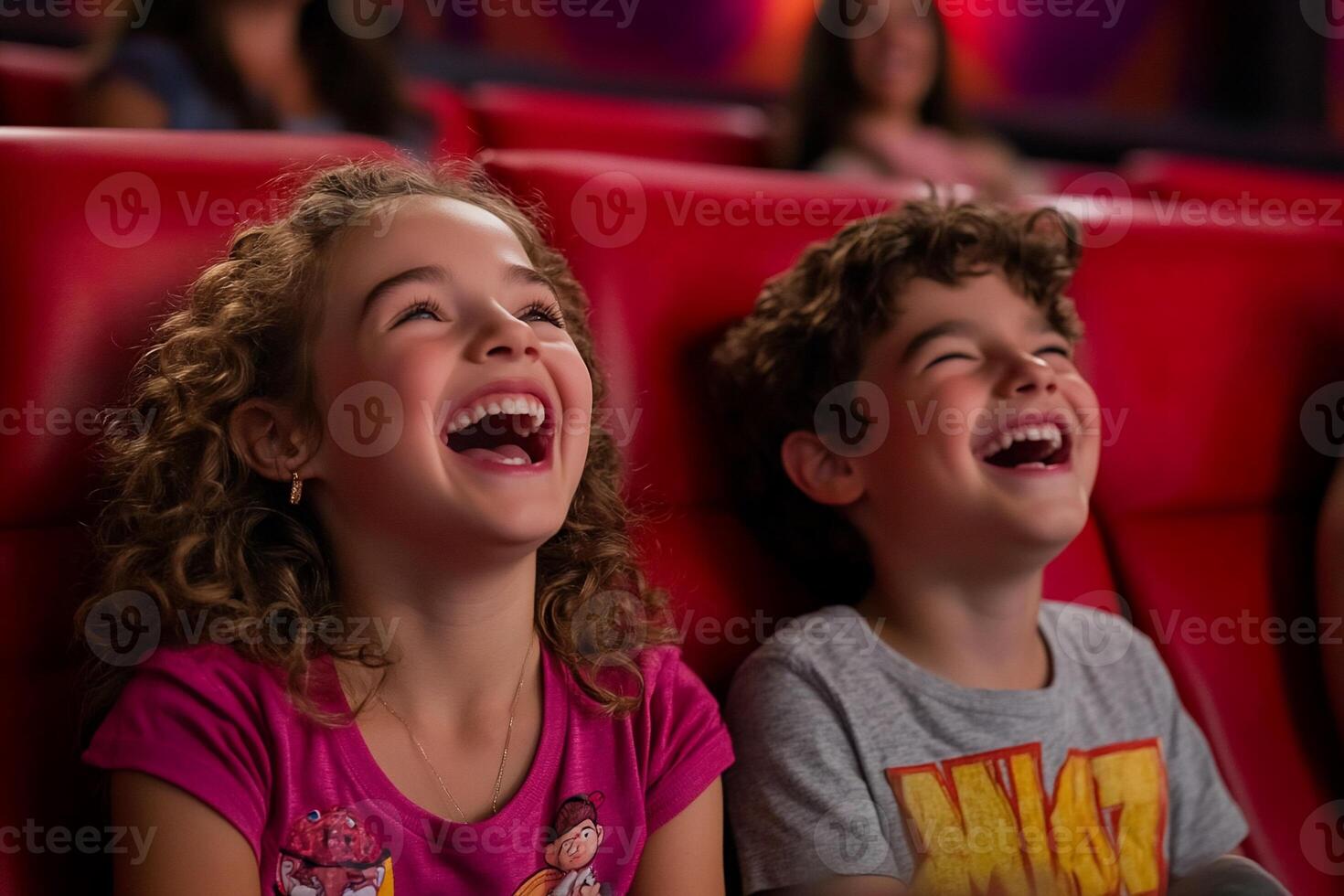 Two children laughing joyfully in a movie theater. photo