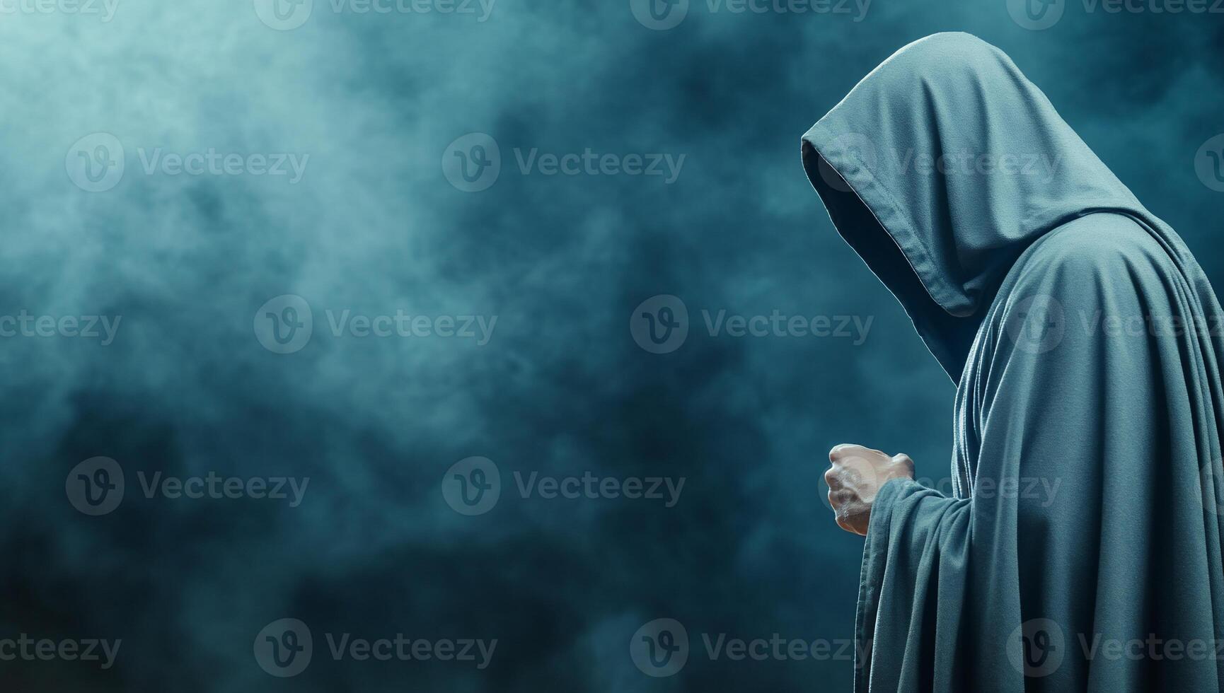 A person in a hooded robe standing in front of a dark background photo