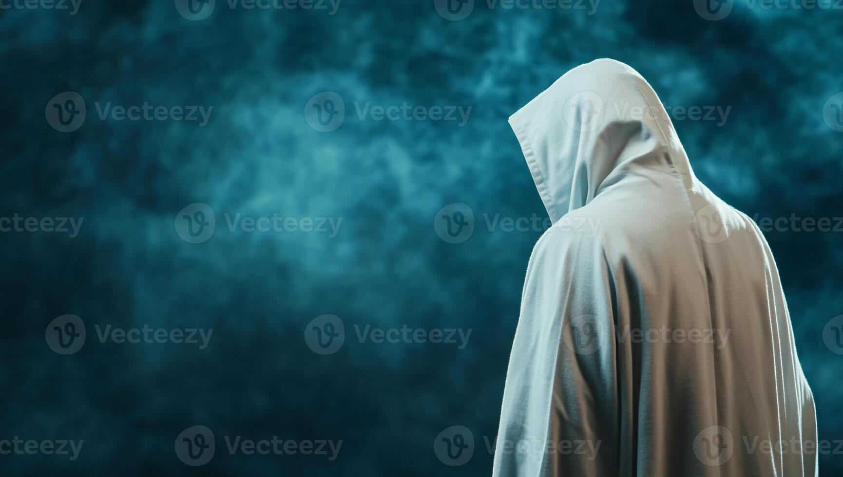 A person in a white robe standing in front of a dark background photo