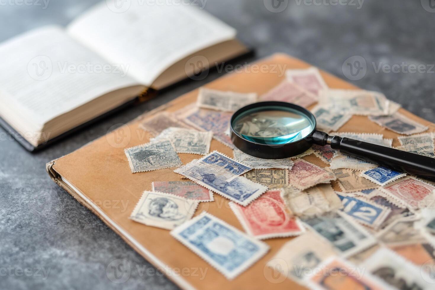 A magnifying glass on a collection of stamps and an open book. photo