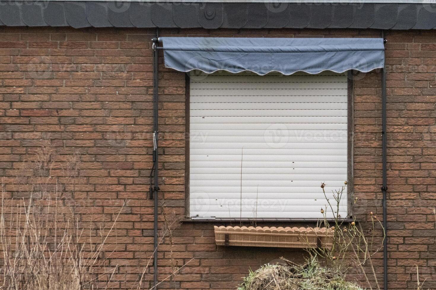 Closed window with blue awning on brick wall photo