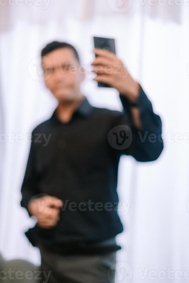 Blurred man capturing a selfie with smartphone in a bright ambient setting photo