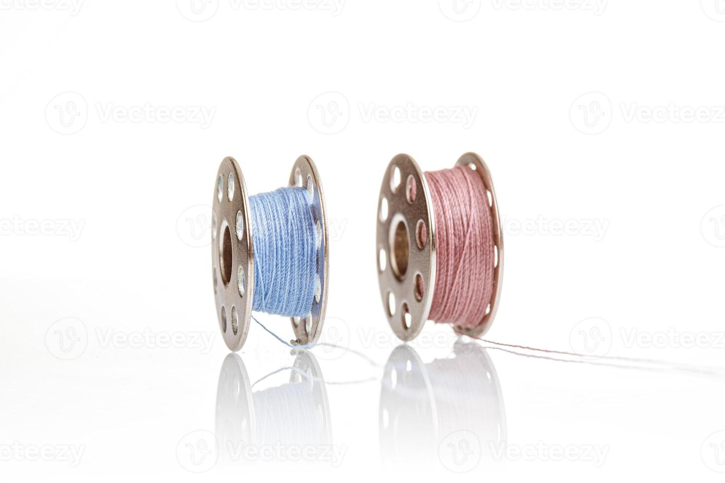 spools of blue and pink thread on a white background close up photo