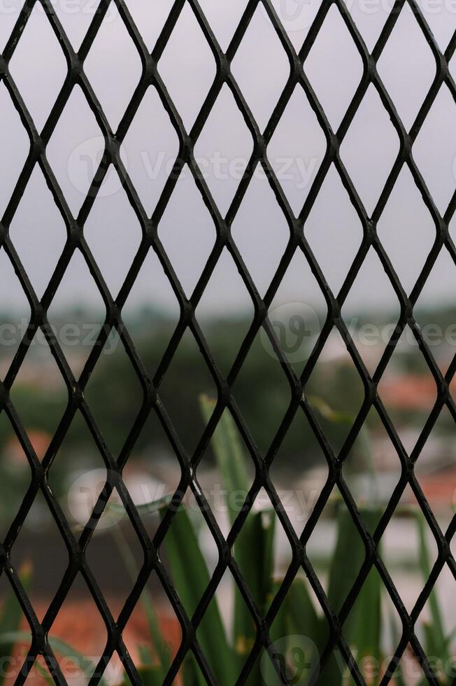Geometric steel mesh fence with blurred urban background on overcast day photo