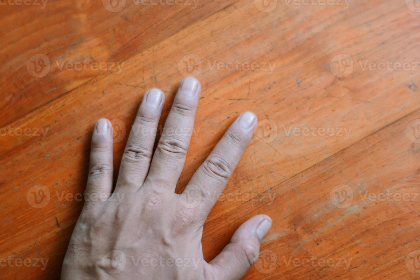 Open hand resting on warm textured wood surface, fingers spread photo