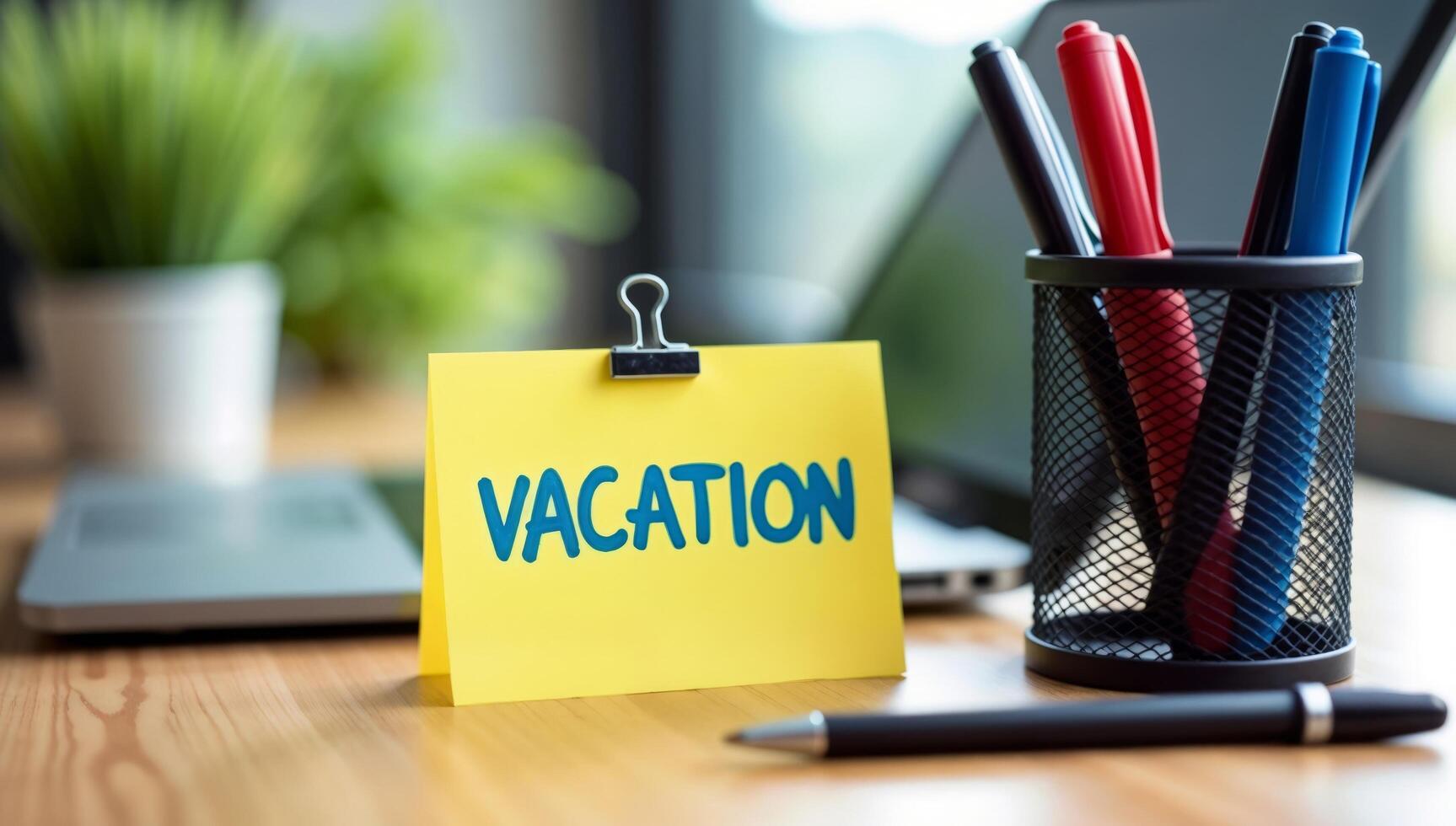 Workplace Desk With Yellow Vacation Note and Office Supplies photo