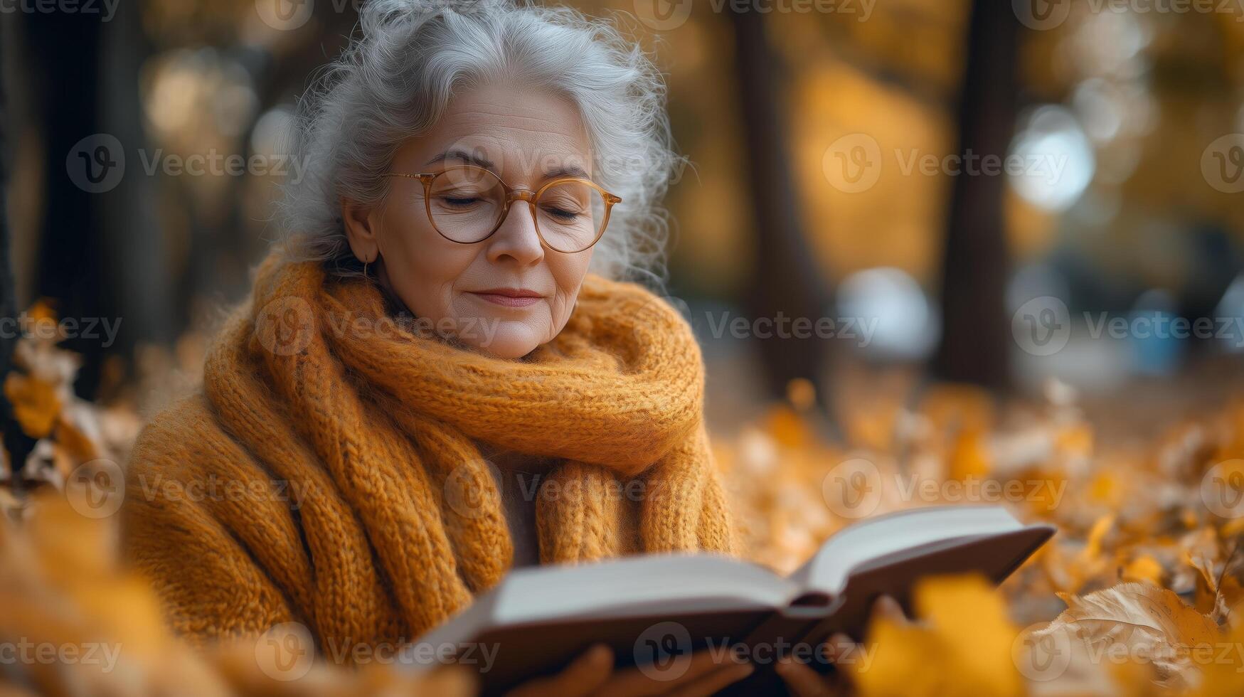 An older woman reading a book in the fall photo